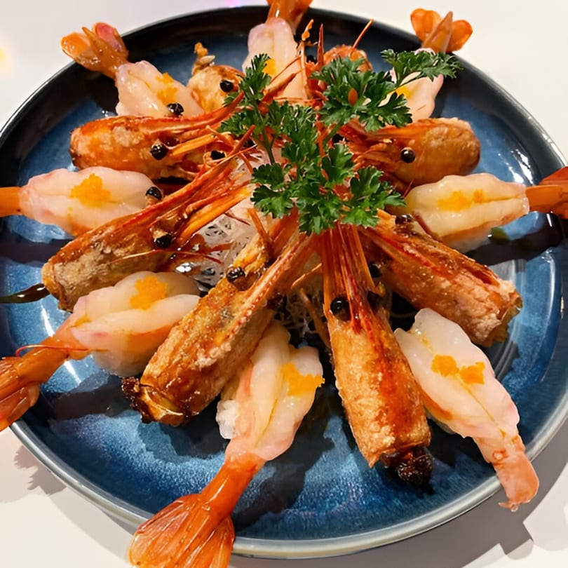 A blue plate of Japanese amaebi nigiri sushi with fried shrimp heads and fresh parsley.